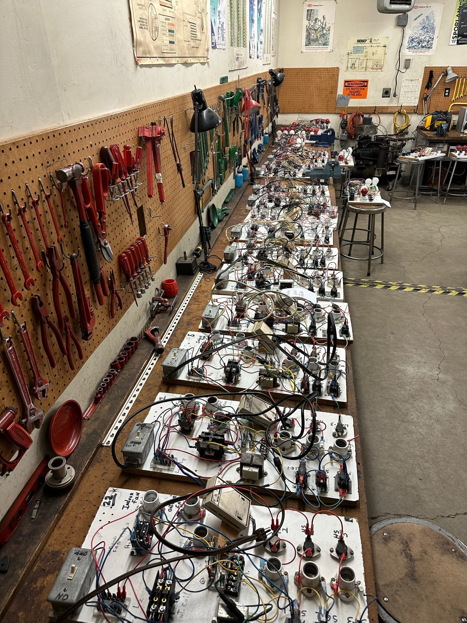 Row of electrical wiring boards with switches, thermostats, and colored wire at student stations