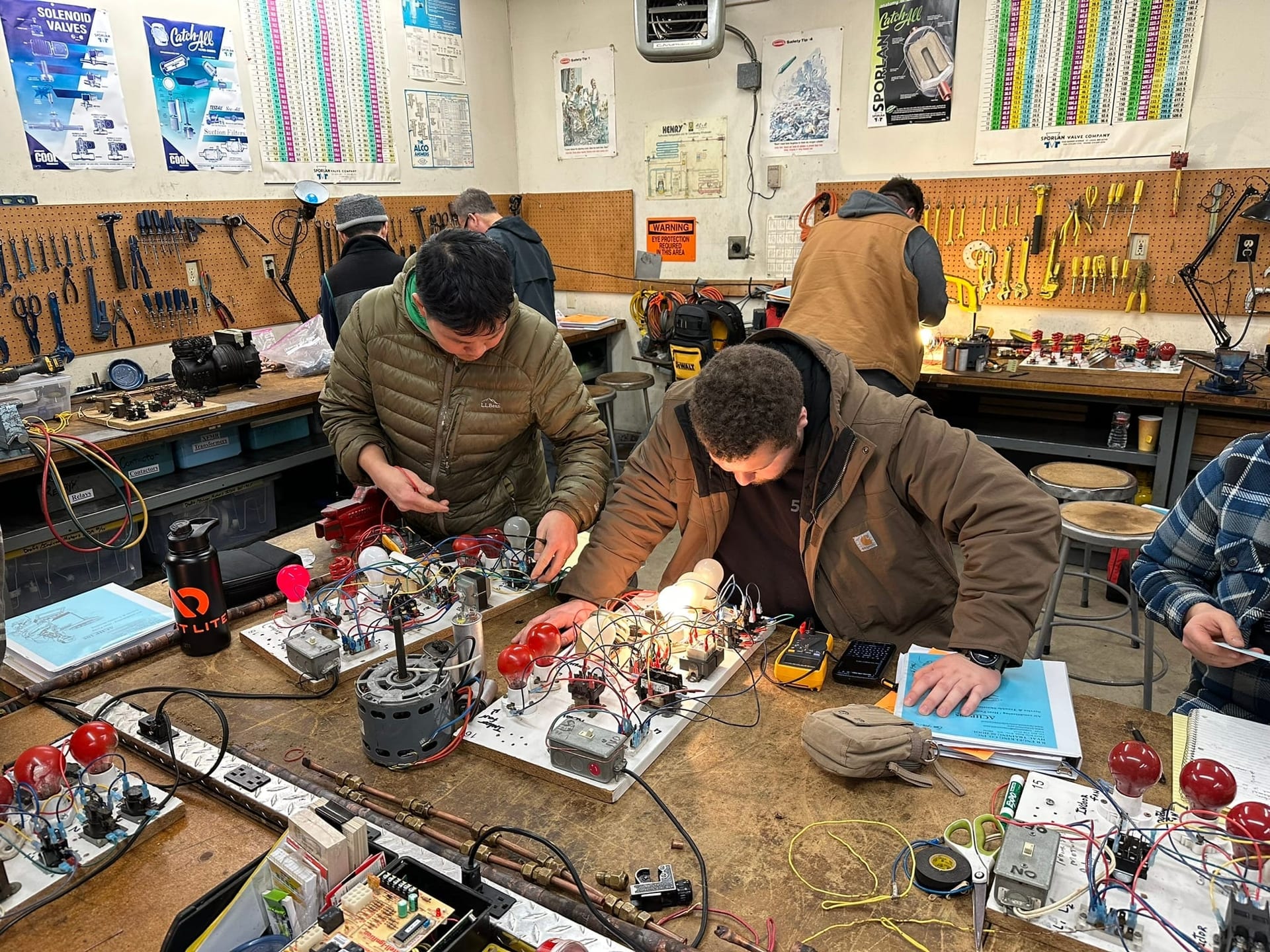 Current HVAC School class with students actively troubleshooting equipment at a workbench station