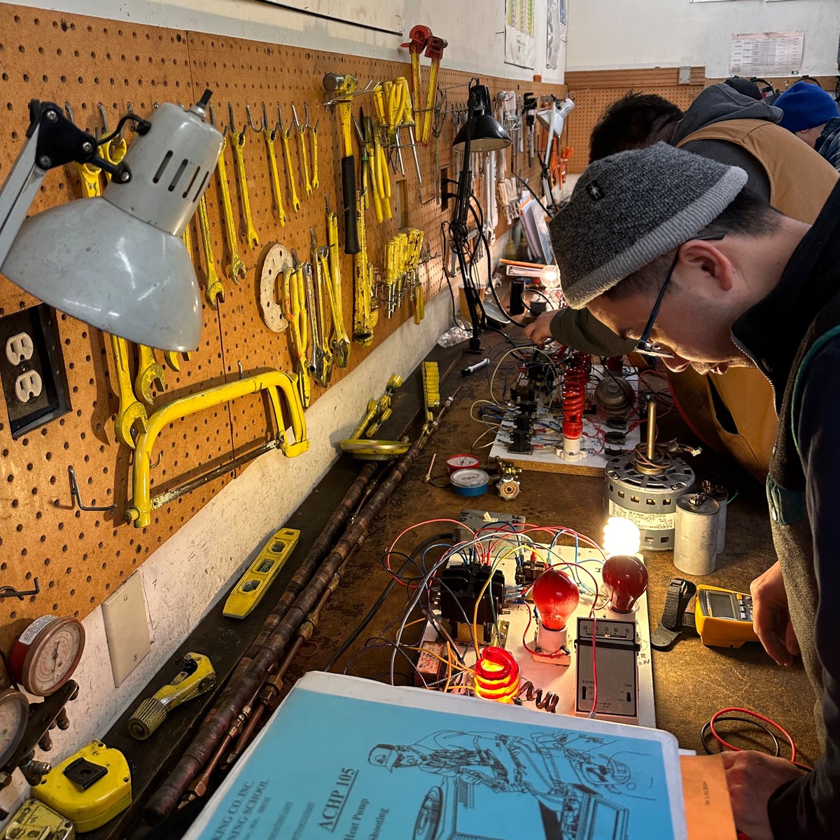 Students at training benches working hands-on with HVAC components