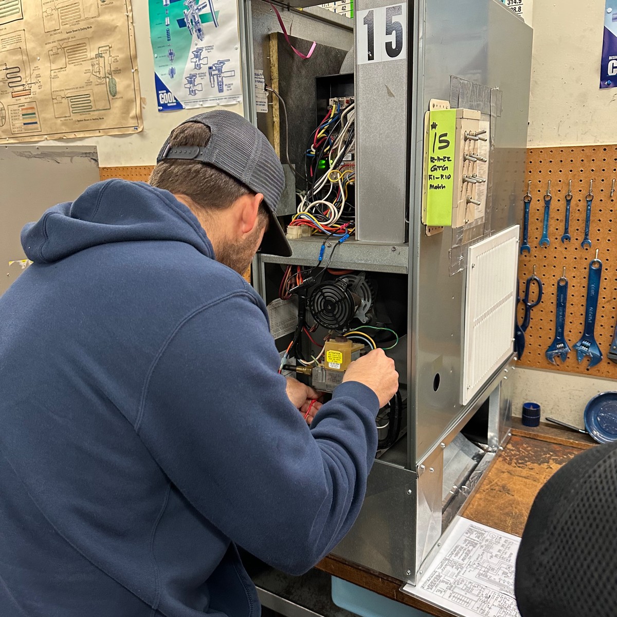 Student at an HVAC training station working on real equipment